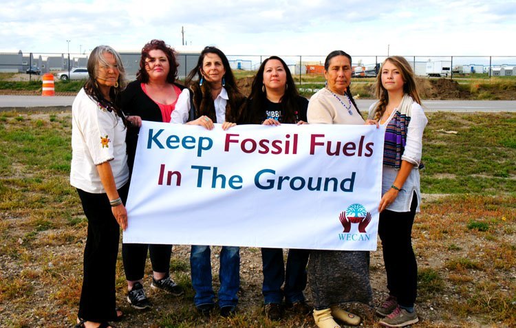 Members of the Women’s Earth and Climate Action Network and Movement Rights stand with Kandi Mossett (center) outside of a ‘man-camp’ in Williston, ND. Photo credit: Emily Arasim Members of the Women’s Earth and Climate Action Network and Movement Rights stand with Kandi Mossett (third from right) outside of a ‘man-camp’ in Williston, North Dakota. Photo credit: Emily Arasim